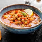 Bowl of moroccan bean soup with lemon slice garnishes.