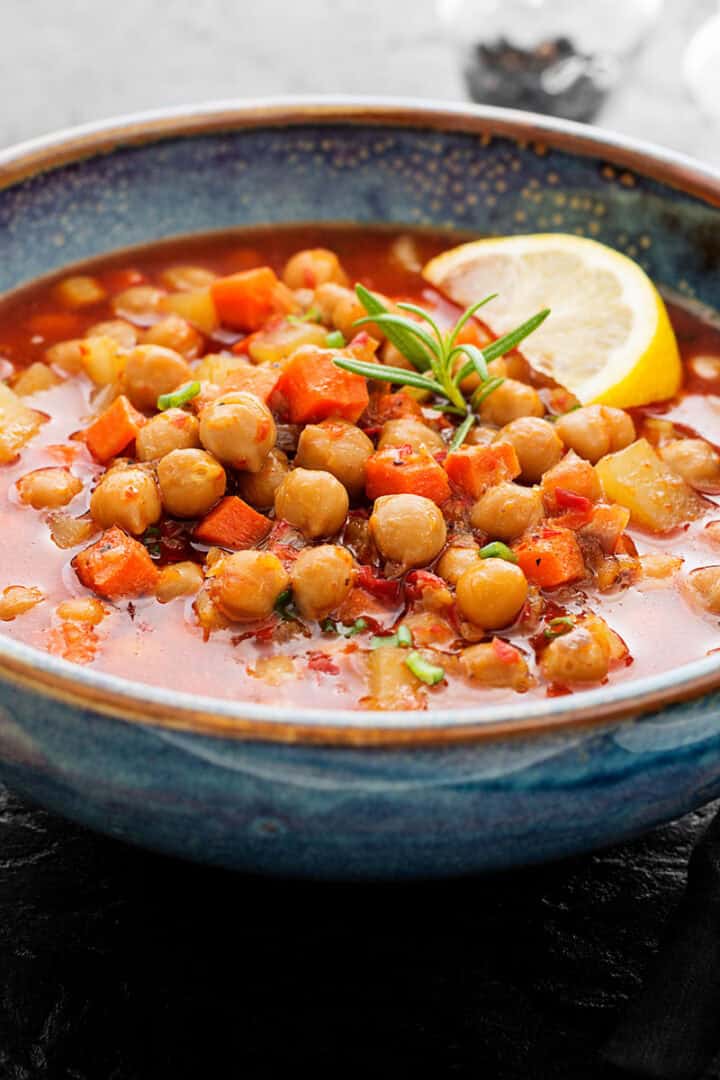 Bowl of moroccan bean soup with lemon slice garnishes.