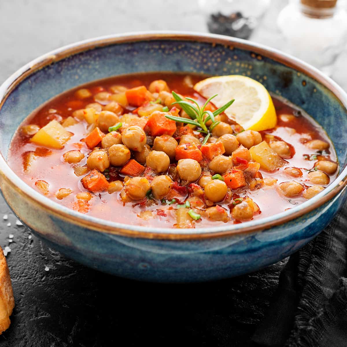 Bowl of moroccan bean soup with lemon slice garnishes.