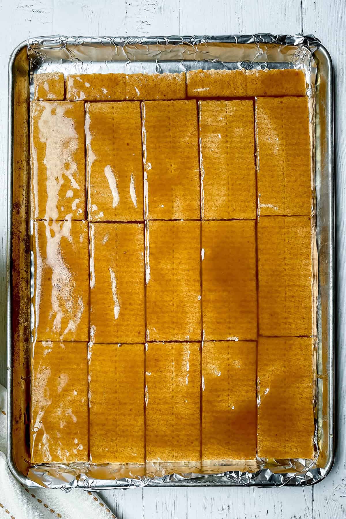 Baking sheet filled with toffee topped graham crackers ready for baking.