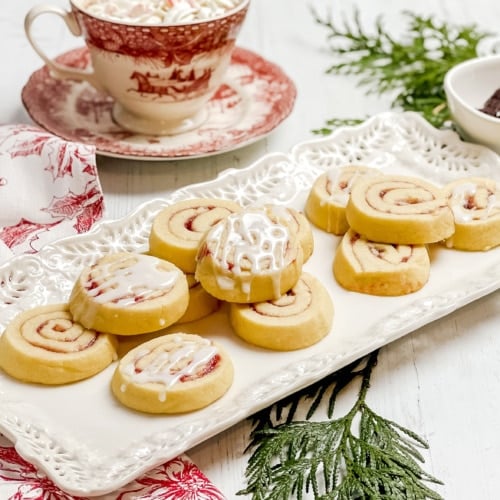 Side view of Raspberry Pinwheel Cookies on a tea tray with vanilla icing.