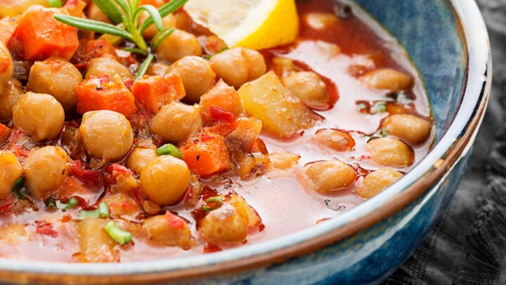 Closeup view of Moroccan Bean Soup in a blue bowl with lemon wedge