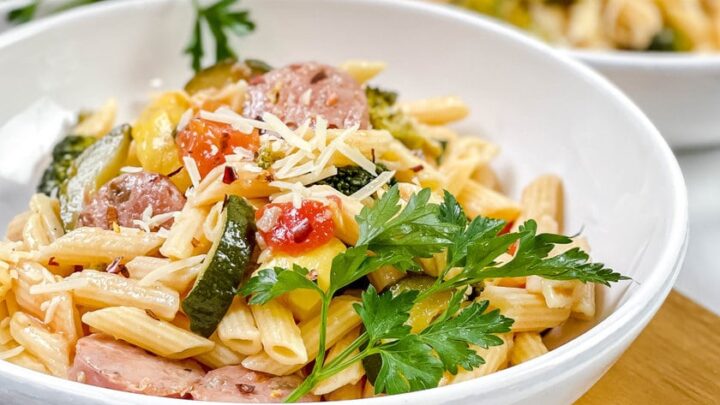 Closeup side view of Sausage Pasta in a white pasta bowl with sausage, zucchini, tomatoes and broccoli