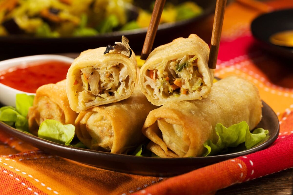Closeup side view of Baked Egg Rolls on a black plate with herbs