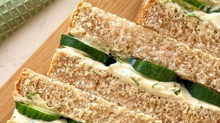 Close up view of vegan cucumber finger sandwiches on wheat bread.