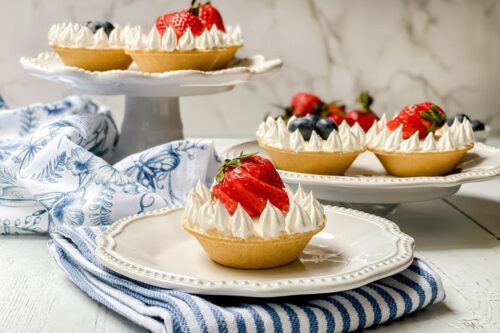 Side view of No Bake Mini Cheesecake garnished with whipped topping and a sliced strawberry