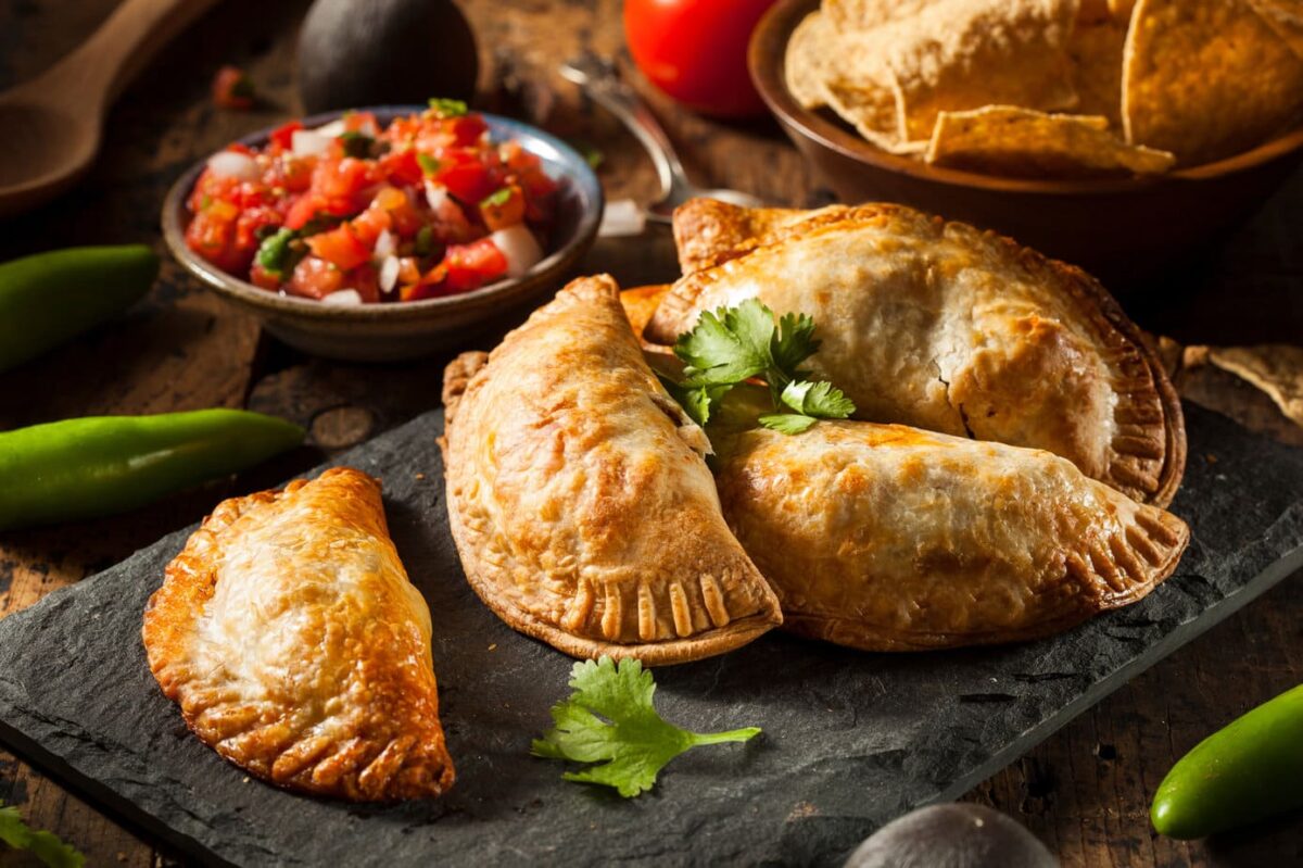 Side view of beef empanadas on a slate board