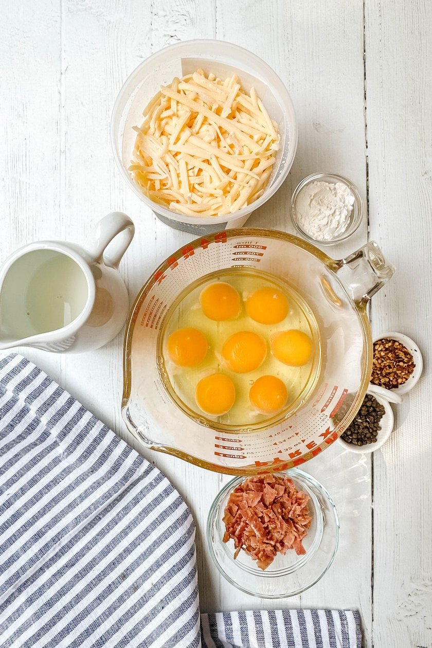 Top view of Egg Bites ingredients on a white wood background