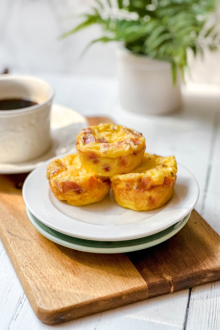 Side view of 3 stacked Bacon Gouda Egg Bites on a wood serving board