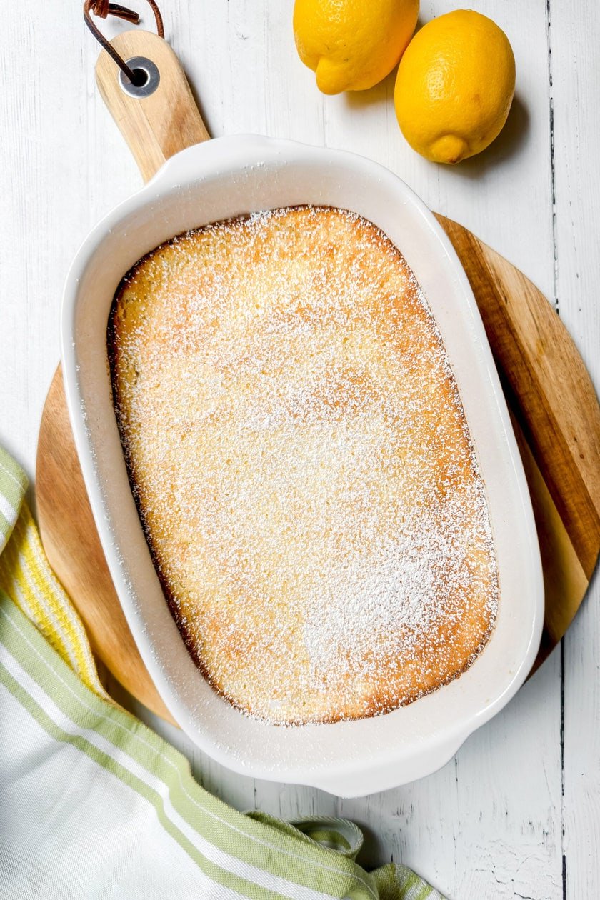 Top view of Baked Lemon Pudding in a white oval baking dish and dusted with powdered sugar