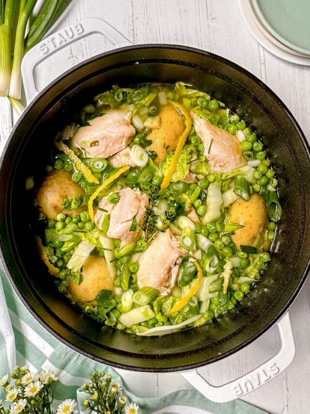 Top view of Spring Chicken Stew with peas and new potatoes in a white Dutch oven