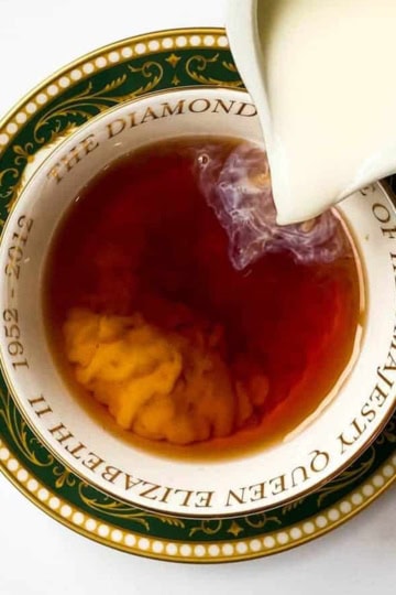 Cream being poured into Irish Breakfast Tea served in a Queen Elizabeth Jubilee teacup.