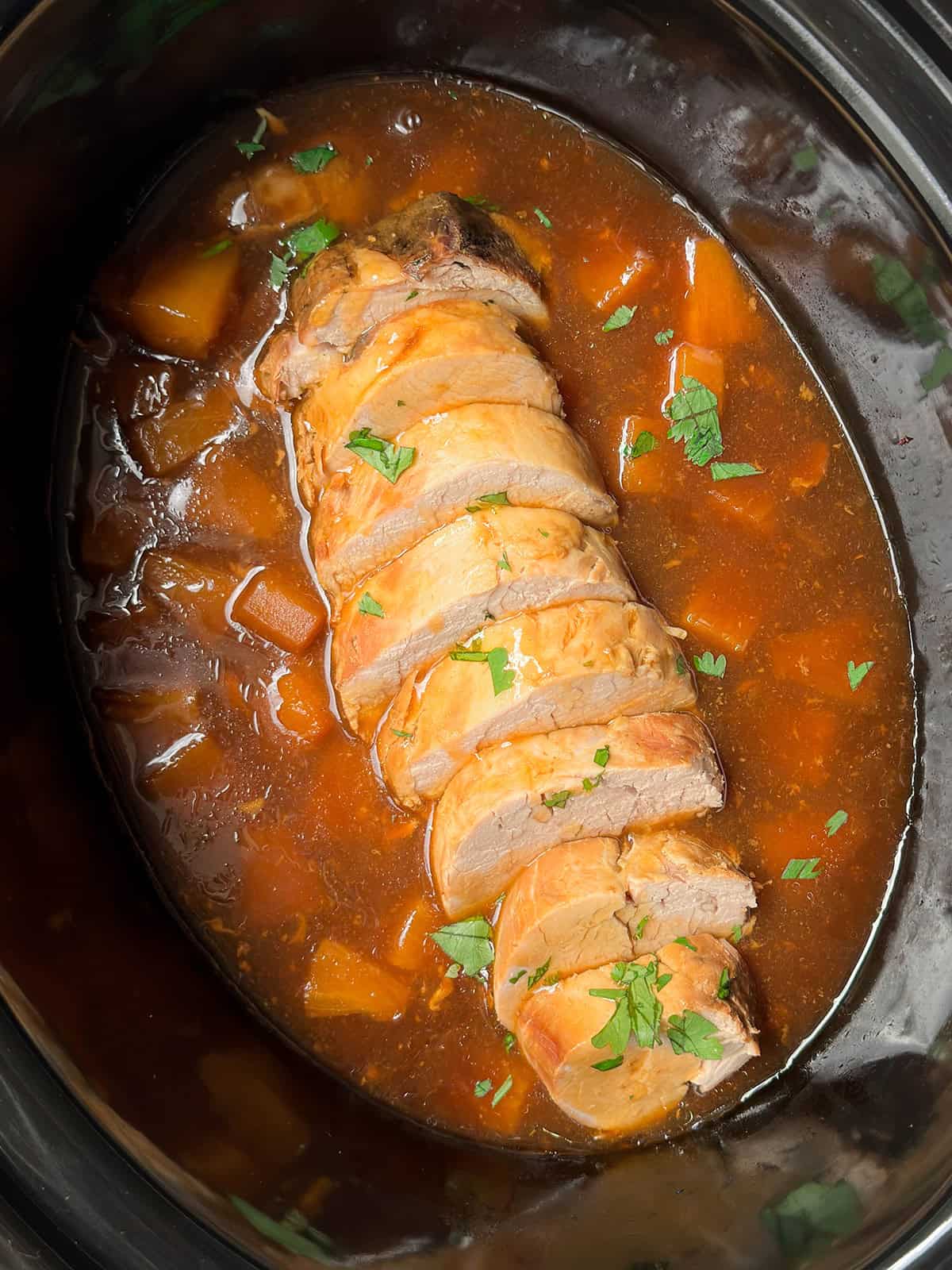 Cooked and sliced pork tenderloin resting in a pineapple teriyaki sauce ready for serving.