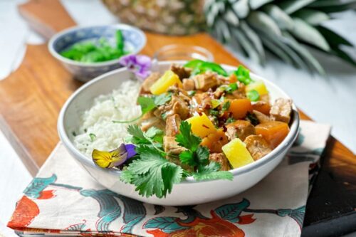 Side view of Crockpot Hawaiian Pork Tenderloin served over coconut rice with cilantro and jalapenos in a white pasta bowl