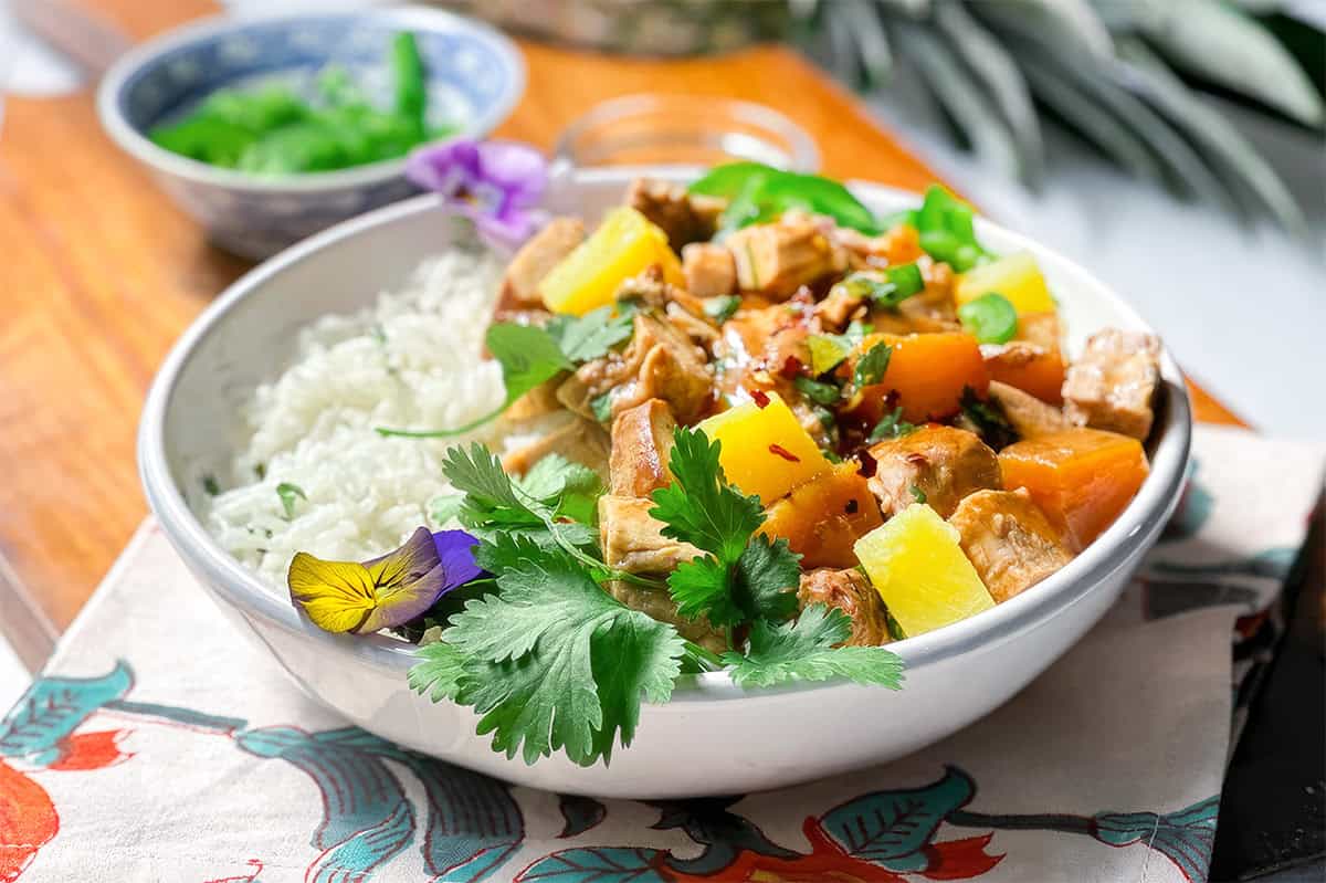 Crockpot pineapple pork tenderloin served over rice with pineapple and fresh cilantro.