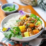 A bowl of coconut rice and pineapple pork in teriyaki sauce garnished with cilantro in a bowl.