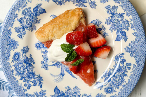 Top diagonal view of Strawberry Rhubarb Tart on a blue and white plate with baby's breath flowers.