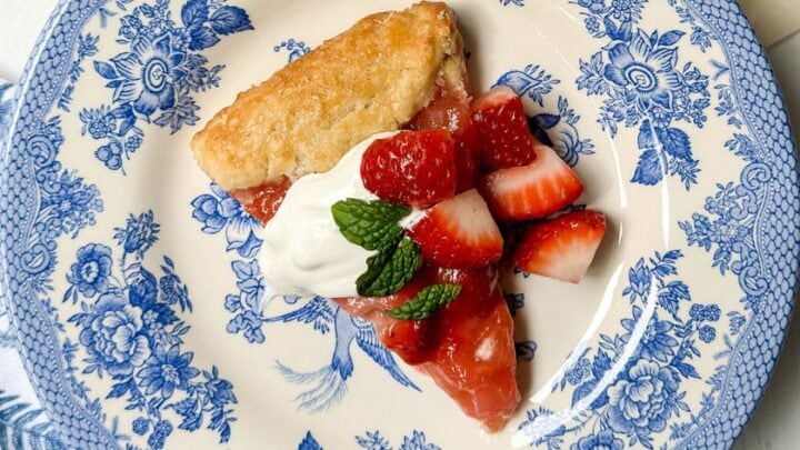 Top diagonal view of Strawberry Rhubarb Tart on a blue and white plate with baby's breath flowers.
