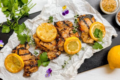 Top view of grilled marinated chicken on a black cutting board