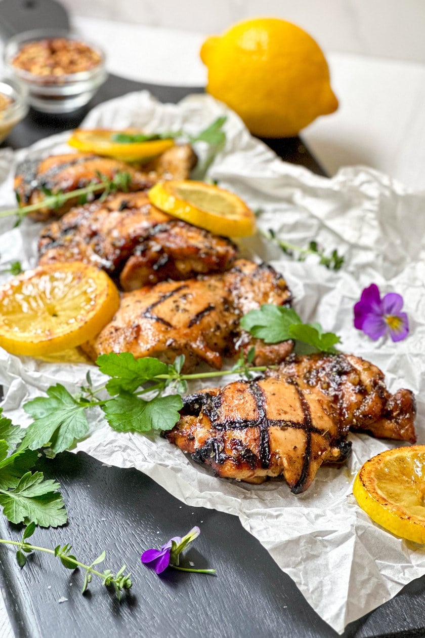 Side view of grilled chicken with fresh parsley and grilled lemons