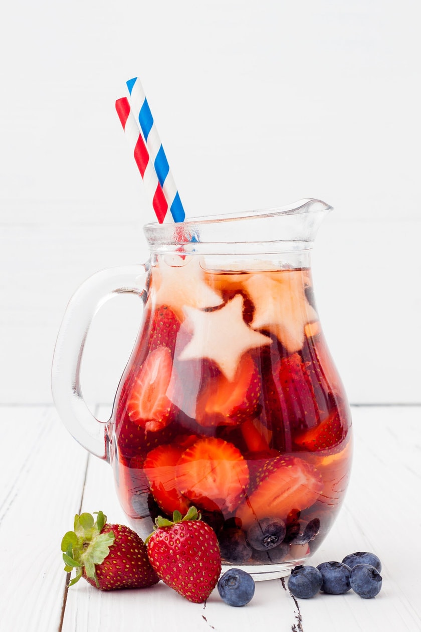 Side view of Non-Alcoholic Red, White, and Blue Sangria in a glass pitcher with red, white, and blue straws
