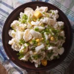 A plate of potato salad recipe with chopped hard-boiled eggs, green onions, and mayonnaise served on a checkered cloth.