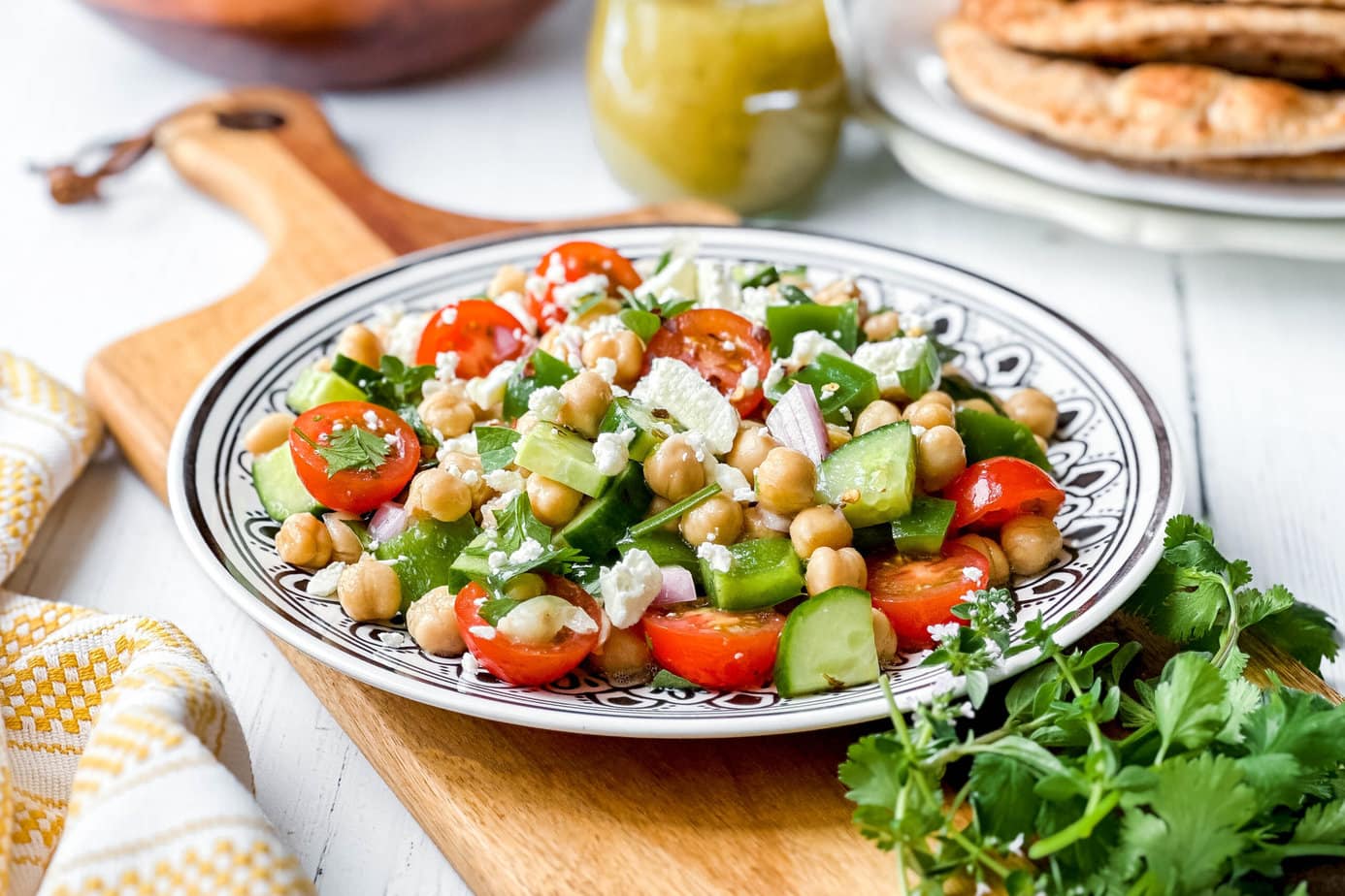 Side view of Chickpea Salad on a black and white plate with feta and cherry tomatoes