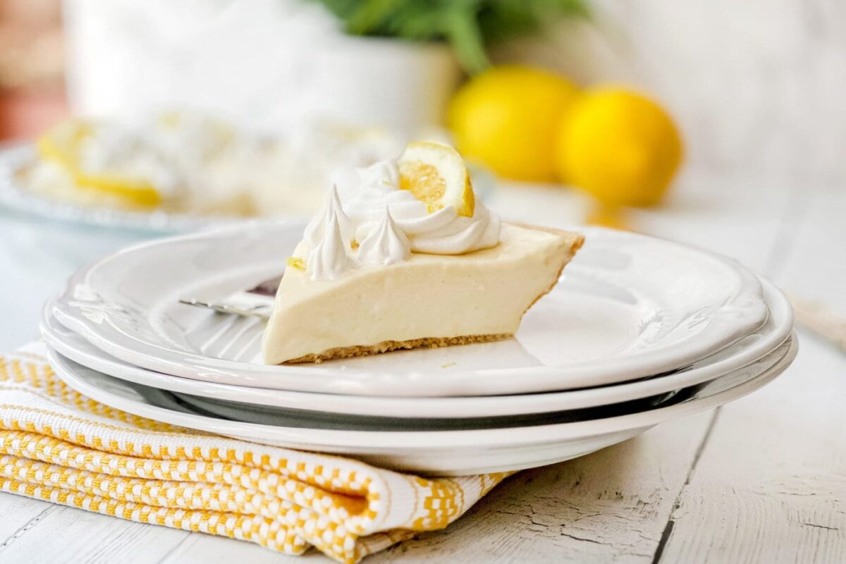 Side view of a slice of No Bake Lemon Pie with whipped topping and fresh lemon slices