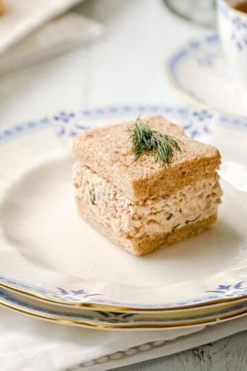 Closeup view of Salmon Salad Tea Sandwich on wheat bread with a sprig of dill