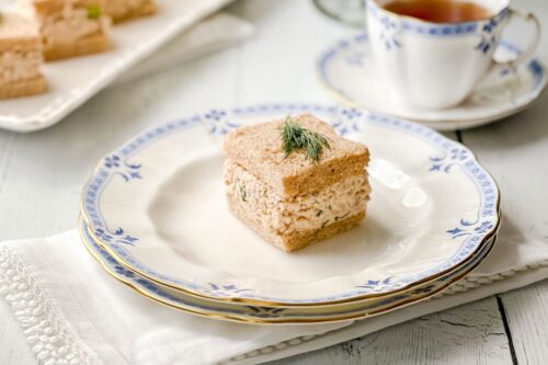 Closeup view of Salmon Salad Tea Sandwich on wheat bread with a sprig of dill