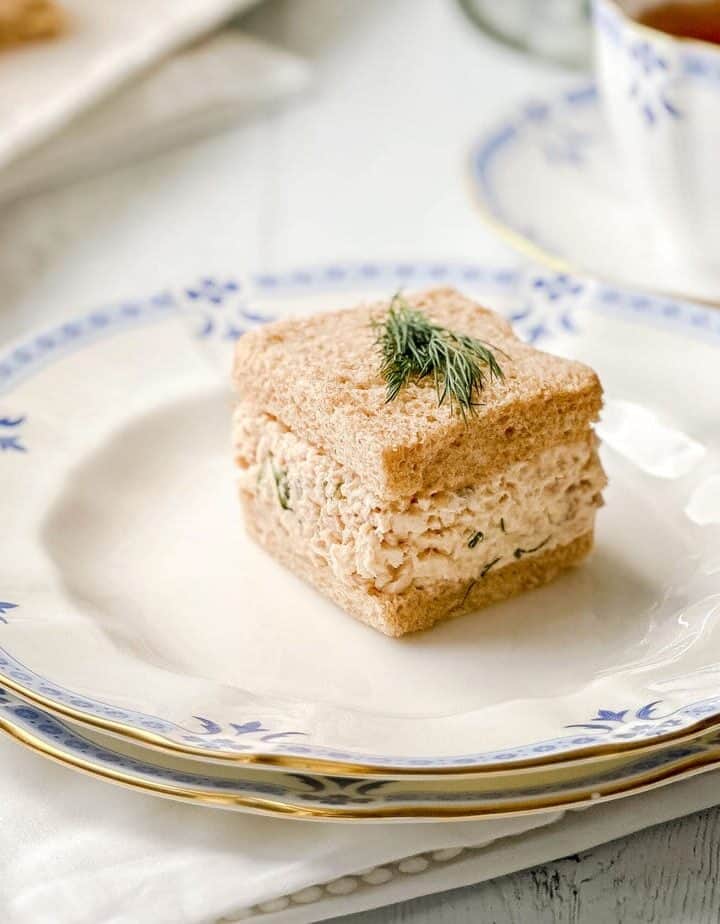 Closeup view of Salmon Salad Tea Sandwich on wheat bread with a sprig of dill