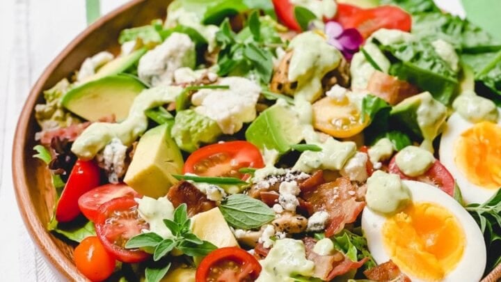 Side view of creamy Chicken Cobb Salad in a bowl with perfectly cooked hard boiled eggs and crispy bacon