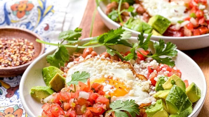 Side closeup view of 2 plates of Huevos Rancheros in a sunny window