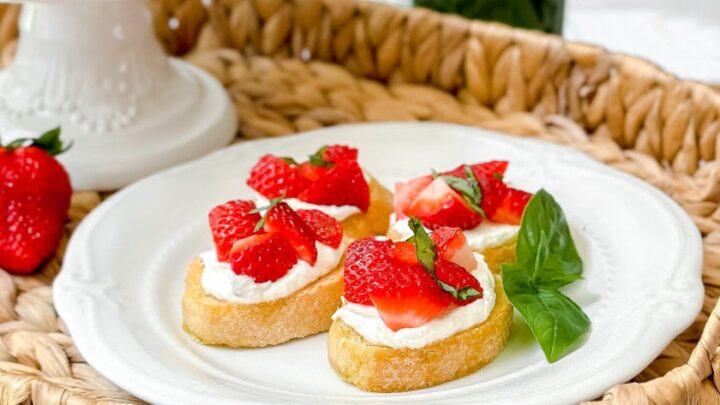 Top side view of 4 strawberry bruschetta on a white scalloped plate