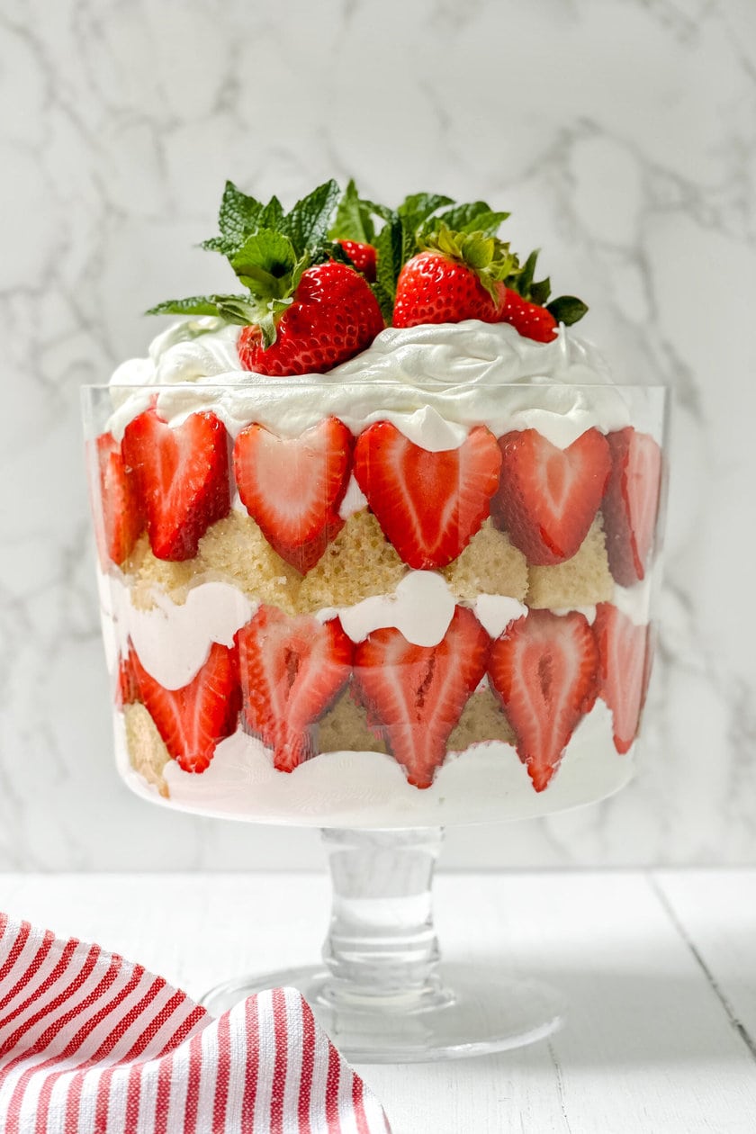 Closeup side view of Strawberry Trifle in a glass trifle dish with a marble background