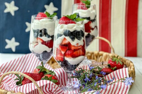 Side view of 3 Red, White, and Blue Berry Parfait glasses in front of an American Flag