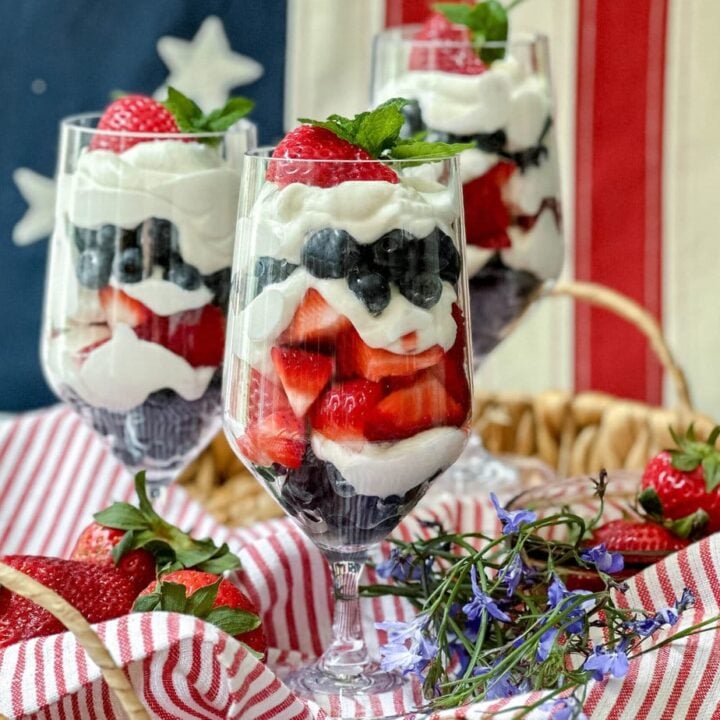 Side view of 3 Red, White, and Blue Berry Parfait glasses in front of an American Flag