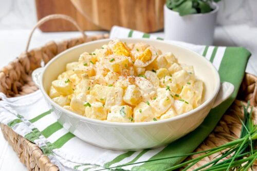 Side front view of Instant Pot Potato Salad with boiled eggs and paprika in a white bowl