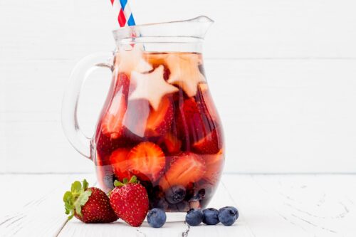 Side view of Non-Alcoholic Sangria in a glass pitcher with strawberries, blueberries and white star shapes