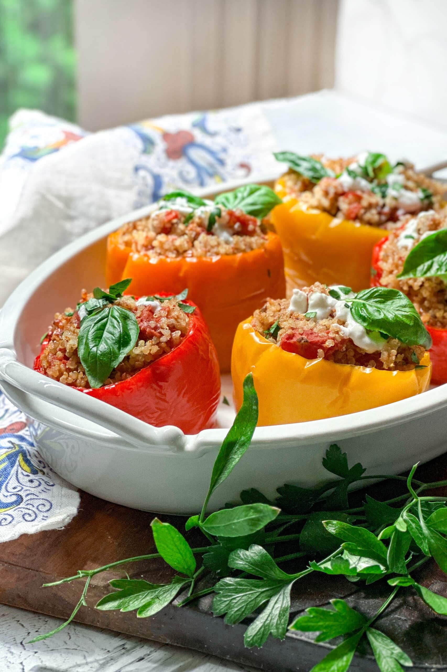 Side view of Crockpot Stuffed Peppers with Quinoa in a serving dish in front of a window