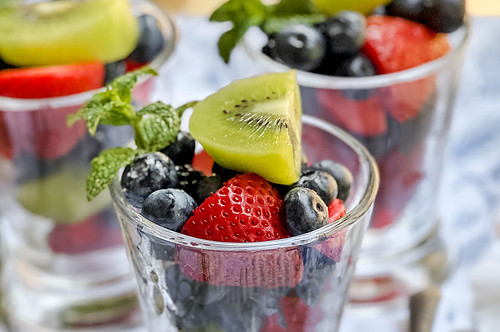 Closeup view of fruit salad with summer berries and kiwi and mint sprigs
