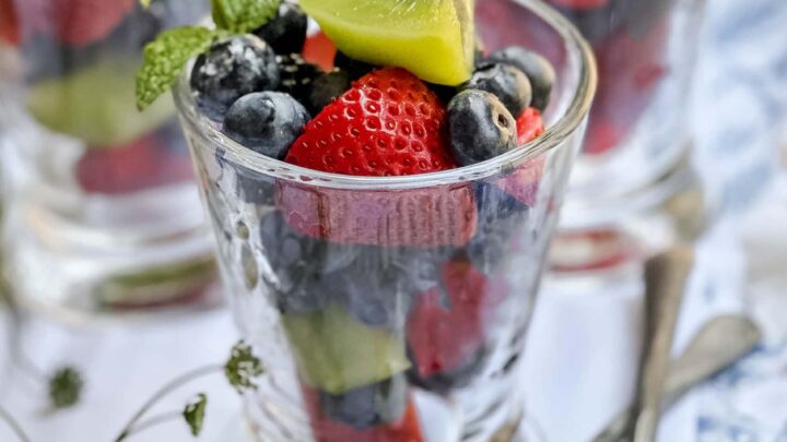Closeup view of fruit salad with summer berries and kiwi and mint sprigs