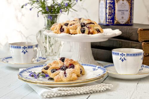 Side view of Blueberry Tarts with Lemon Curd on a plate and serving stand with Darjeeling tea.