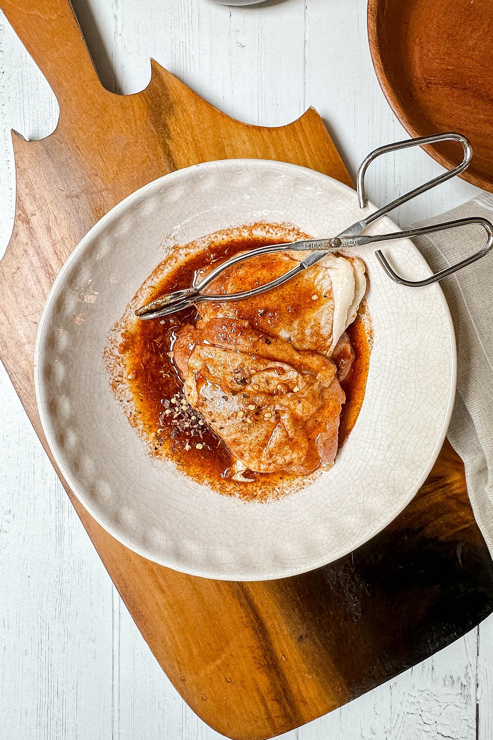 Top view of uncooked chicken coated with Paprika Sauce in a white bowl