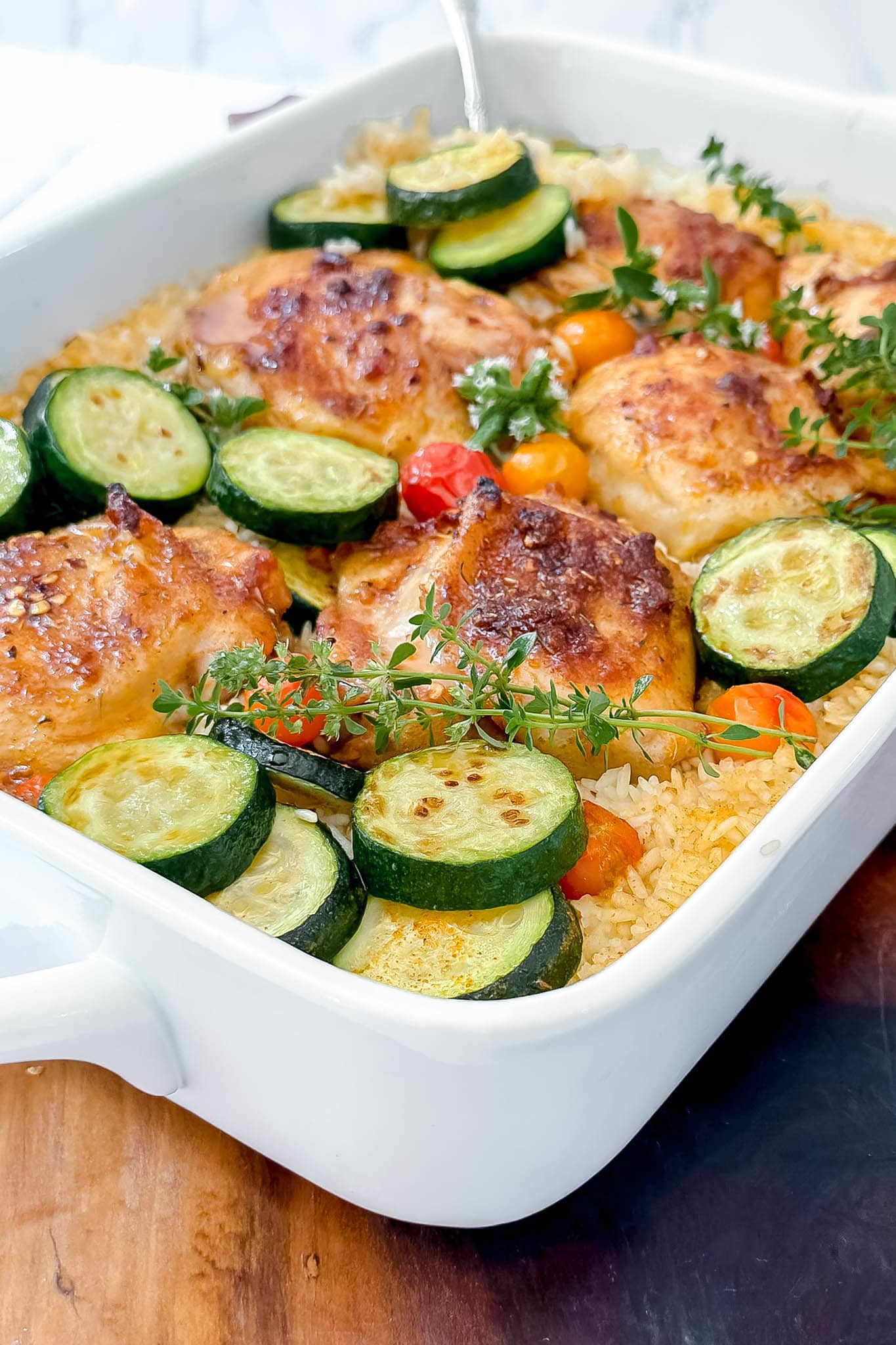 Closeup view of One Pan Chicken and Rice with zucchini, cherry tomatoes, and fresh thyme.