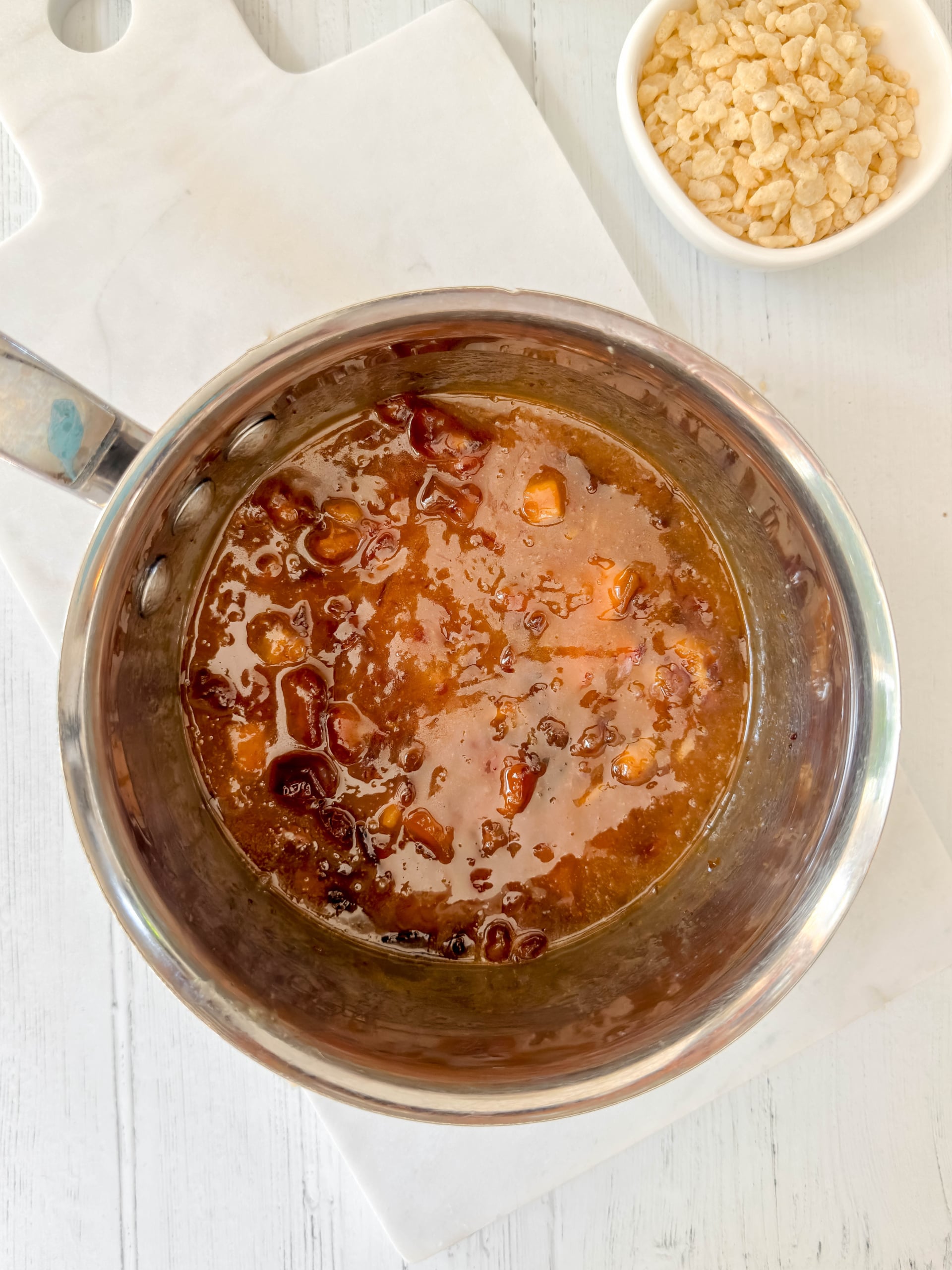 Cooked date mixture in a saucepan beside a bowl of crisp rice cereal.