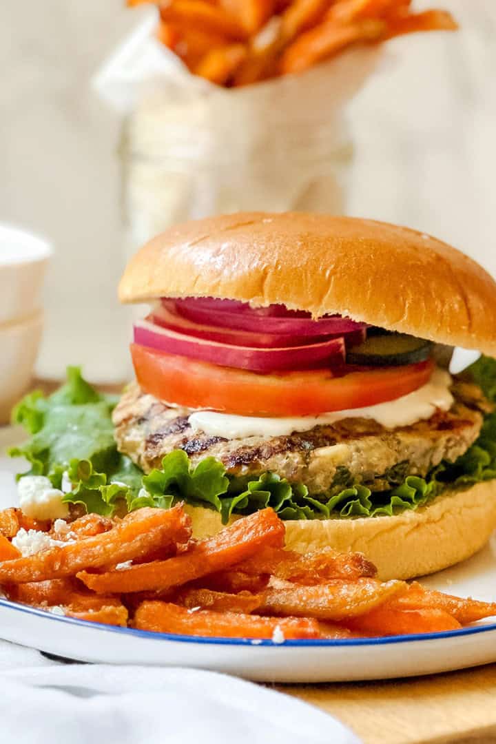Greek turkey burger with feta and herbs served on a bun with fresh toppings.