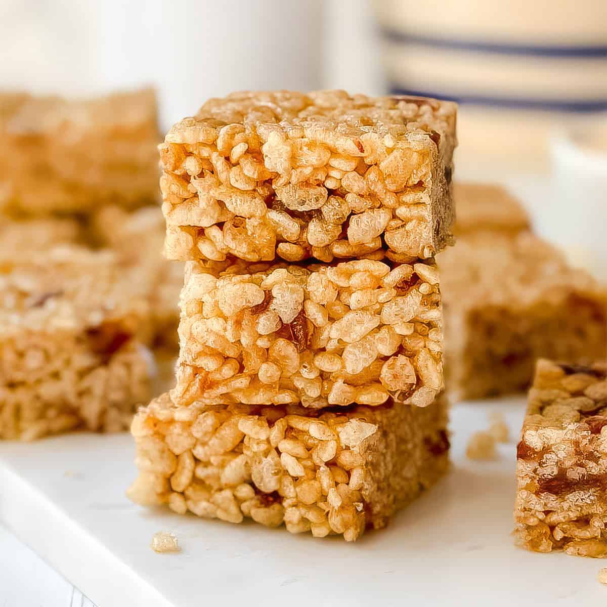 Three Rice Bubble Slice squares are stacked on a white surface, with more slices visible in the background.