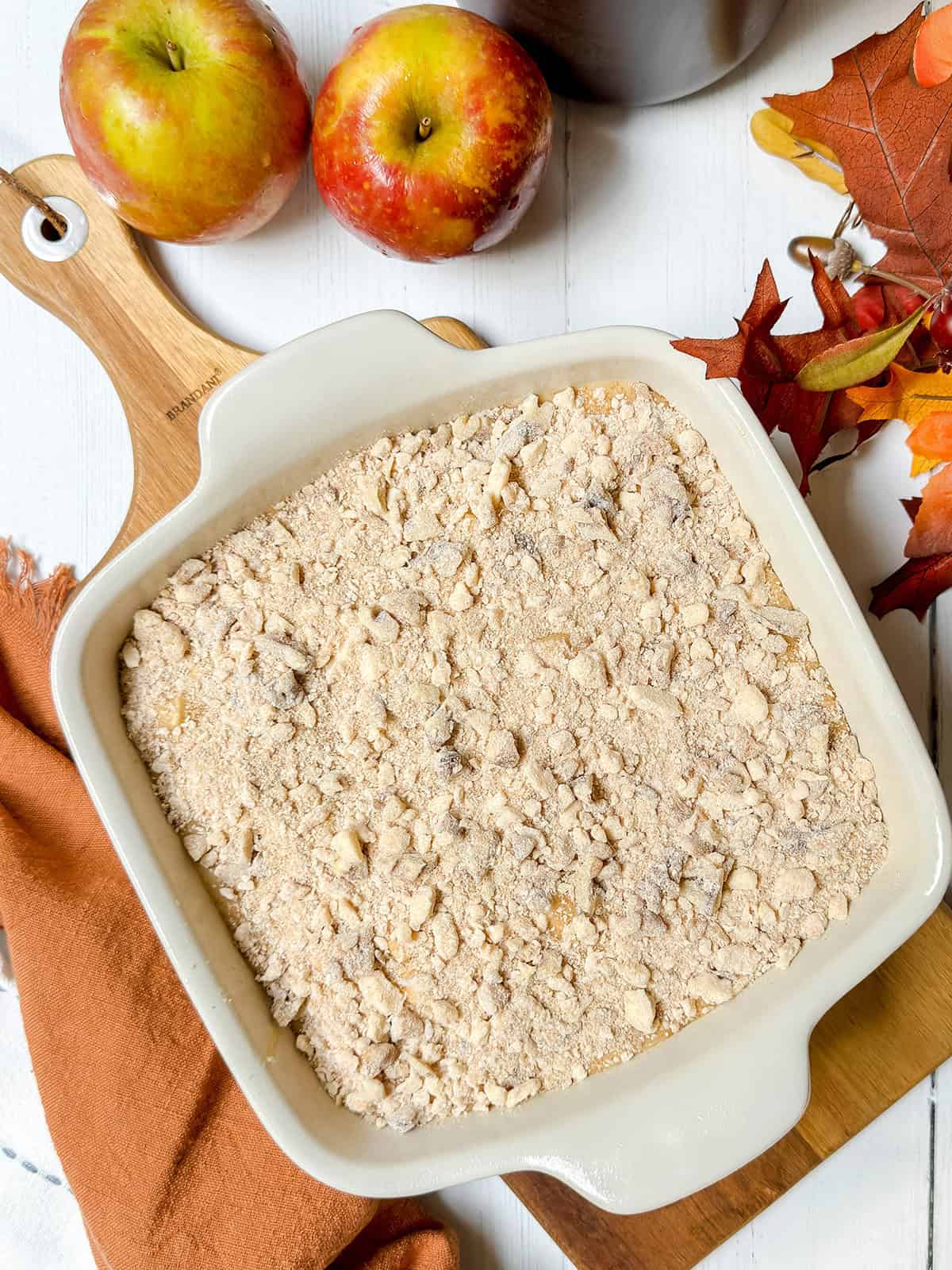 Unbaked apple coffee cake ready for the oven with a pecan streusel topping.