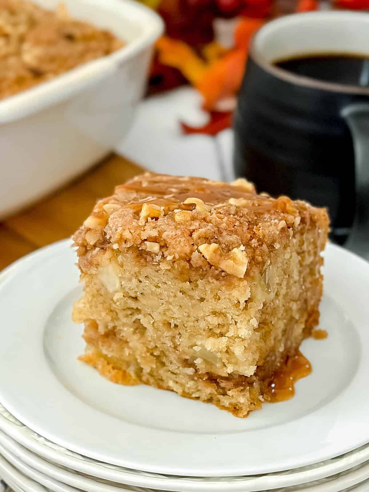 Serving of apple coffee cake with a golden pecan streusel and drizzled with caramel sauce.